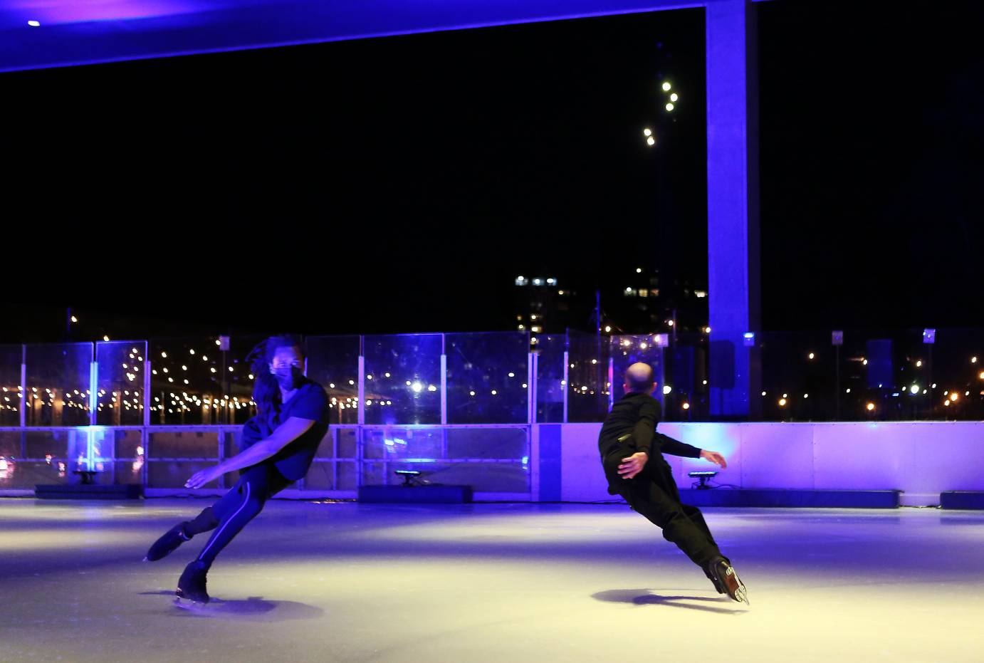 Two skaters stroke across the ice, passing each other